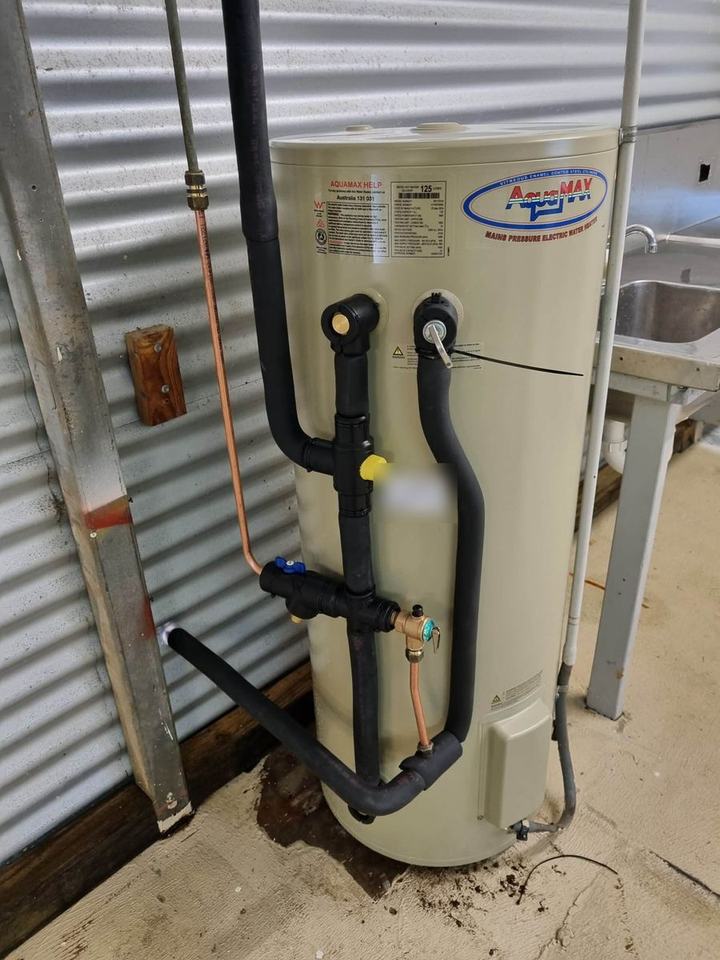 An outdoor hot water unit against a corrugated wall